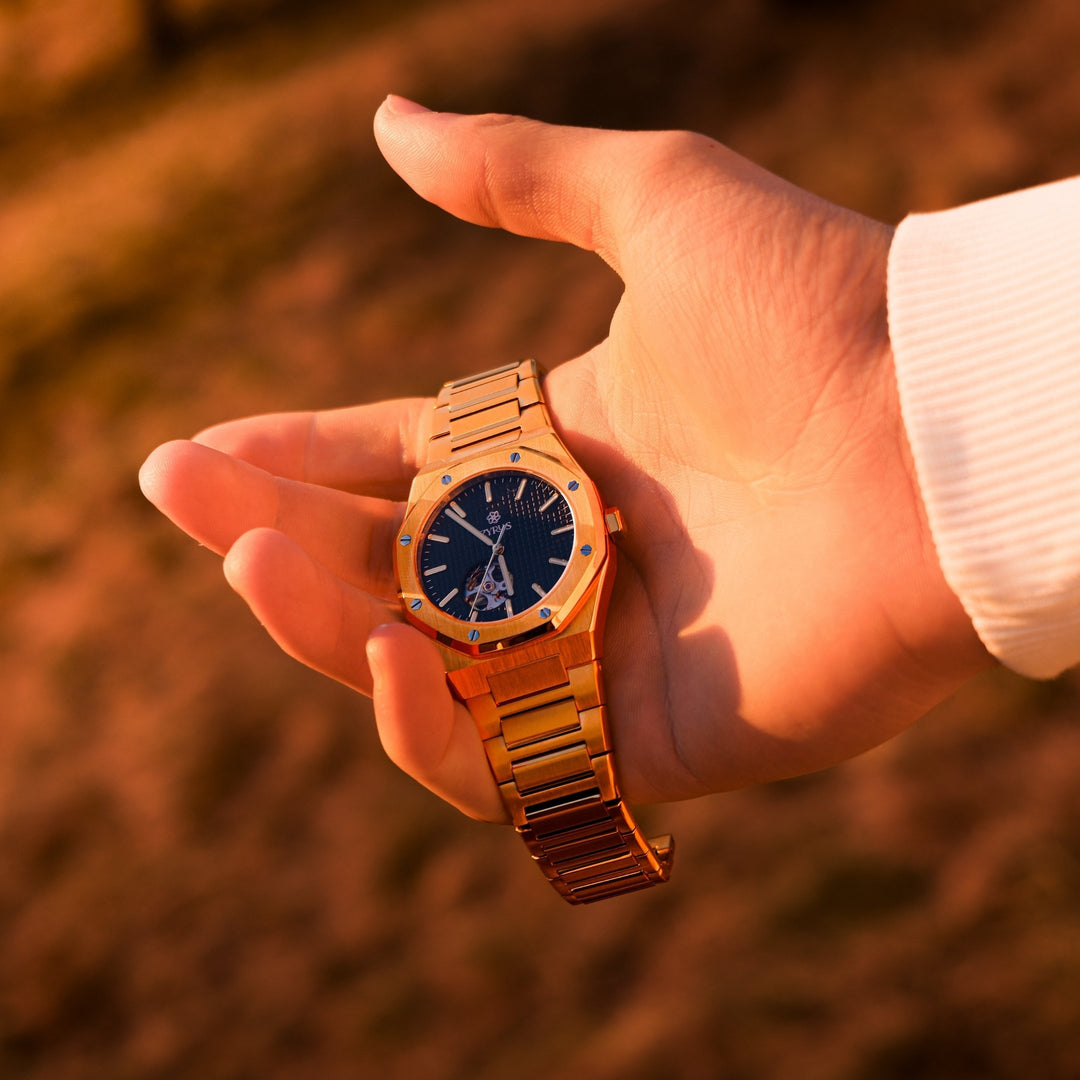 Zyrus Open Heart Watch in gold, showcased against a stunning sunset background, elegantly held to highlight its craftsmanship and design.